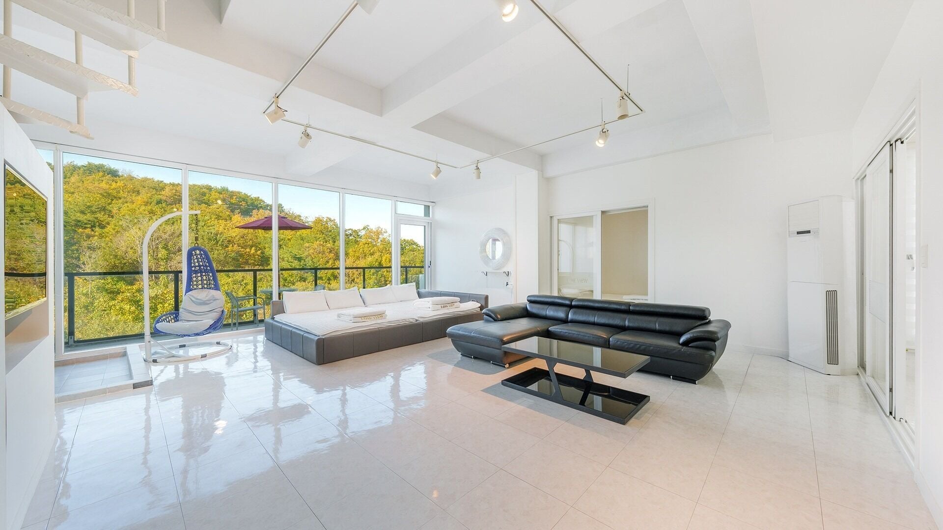 Un salón amplio con un gran ventanal, un sofá, una mesa de centro y un sillón colgante.