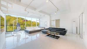 A spacious living area with a large window, a sofa, a coffee table, and a hanging chair. - Gyeongju Lineview Poolvilla (Gyeongju)