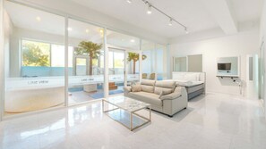 A modern hotel room with a bed, sofa, and a glass wall offering a view of the outdoors. - Gyeongju Lineview Poolvilla (Gyeongju)