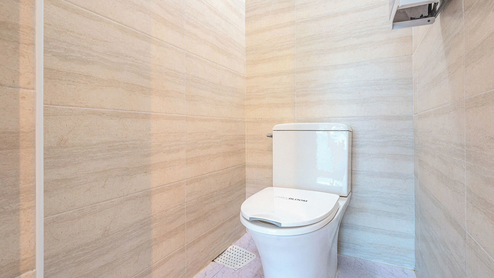 Een badkamer met toilet, betegelde wanden en een douchecabine.