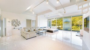 A spacious living room with a modern sofa, a coffee table, and a large window offering a view of greenery. - Gyeongju Lineview Poolvilla (Gyeongju)