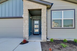 Une maison avec un porche en pierre, une porte d’entrée et une fenêtre avec des stores.
