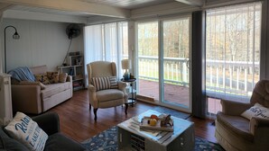 A cozy living room with a beige sofa, a striped armchair, and a coffee table with decorative items. - Lovely 3BR/2BA Lakehouse Retreat in Gated Dubois, PA—Near Beach, Woods & Privacy (DuBois)