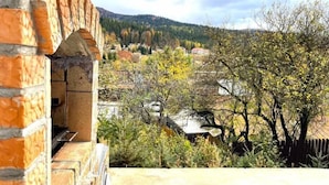 A stone building with a window overlooking a rural landscape with trees and a distant mountain. - Mountain Escape Chalet - BBQ and Mountain View (Bușteni)