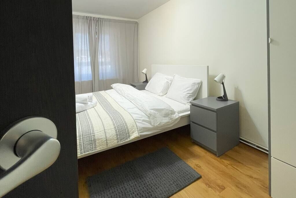 A modern bedroom with a bed, bedside tables, and a nightstand.