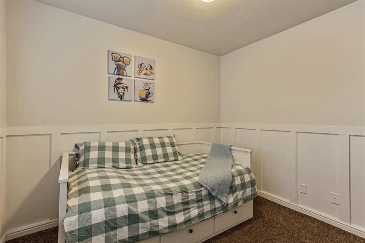 Un dormitorio con cama, paredes blancas y varias fotografías enmarcadas en la pared.