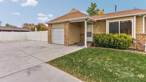 Een gelijkvloers huis met garage, een overdekte veranda en een verzorgd gazon.