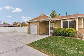 A single-story house with a garage, a covered porch, and a well-maintained lawn.