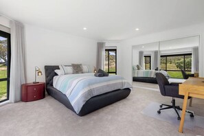 Une chambre moderne avec un grand lit, un bureau et une vue sur l’extérieur.