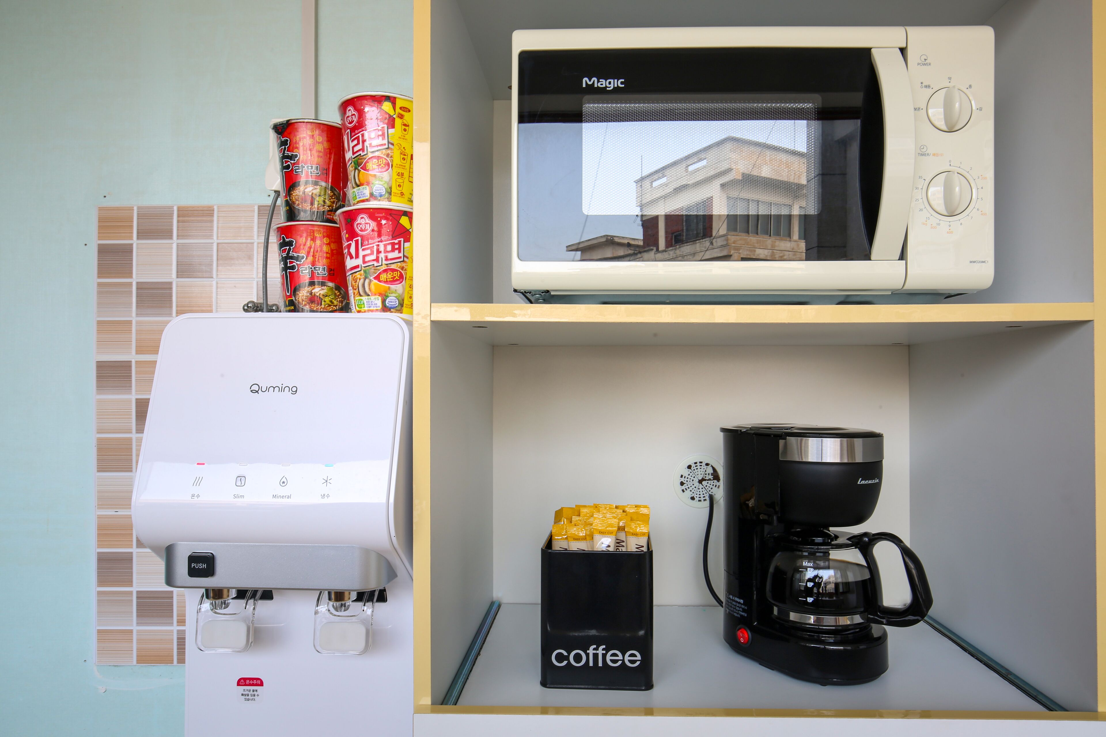 Cozinha equipada com micro-ondas, cafeteira e dispensador de café.