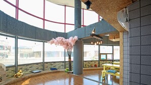 A spacious indoor area with large windows, wooden flooring, and a central pillar. - Dashim Guest House (Gunsan)