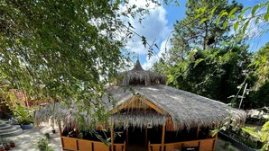 A thatched-roof structure with a staircase leading to it, surrounded by lush greenery and potted plants. - Myat Saytaman Traditional Bamboo House (Kalaw)