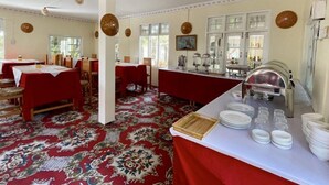 A dining area with tables set for service, a buffet line with food and drinks, and a patterned carpet. - Myat Saytaman Traditional Bamboo House (Kalaw)