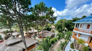 A resort with thatched-roof huts, a white building with orange accents, and a winding pathway. - Myat Saytaman Traditional Bamboo House (Kalaw)