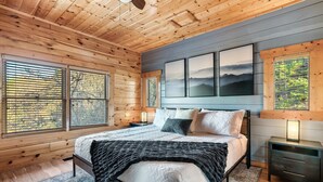 Ein Schlafzimmer mit Holzwandverkleidung, einem Bett, Nachttischen und Bildern an der Wand.