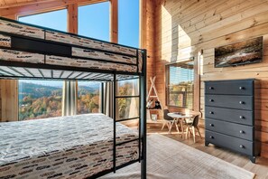A bunk bed with a patterned mattress, a desk with a chair, a dresser, and a painting on the wall. - 5 Starr Views! Hot Tub Games. Sleeps 20 5 BR 4.5 baths. Close to Dollywood (Sevierville)