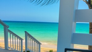 Two wine glasses on a glass table with a view of a beach and a staircase. - The Suite Life (Rokers Point)