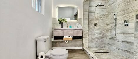 A modern bathroom with a toilet, sink, and shower.
