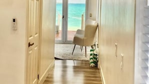 A hallway with a ceiling fan, a clock, and a view of the ocean through glass doors. - The Suite Life (Rokers Point)