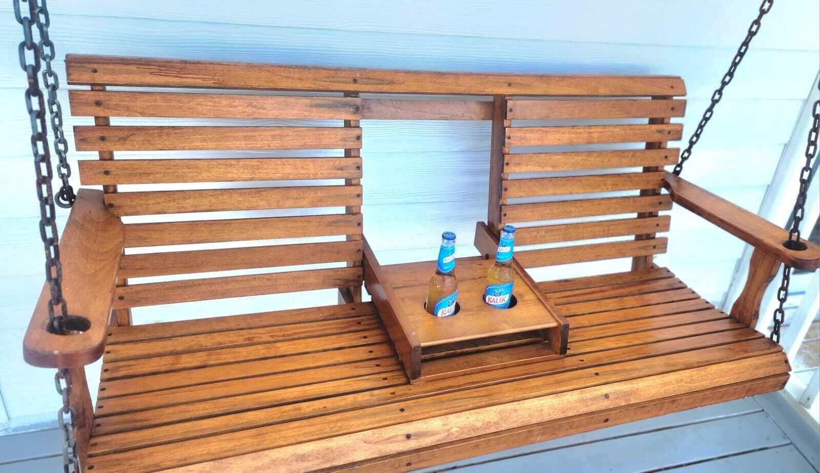 A wooden swing bench with two bottles of Kalik beer on a small wooden table.