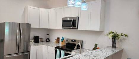 A modern kitchen with white cabinets, stainless steel appliances, a granite countertop, and a vase with flowers on the island.