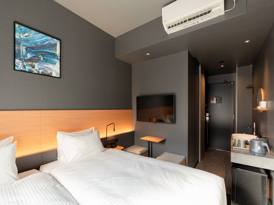 A modern hotel room with a large bed, a desk, a flat-screen TV, and a painting on the wall.