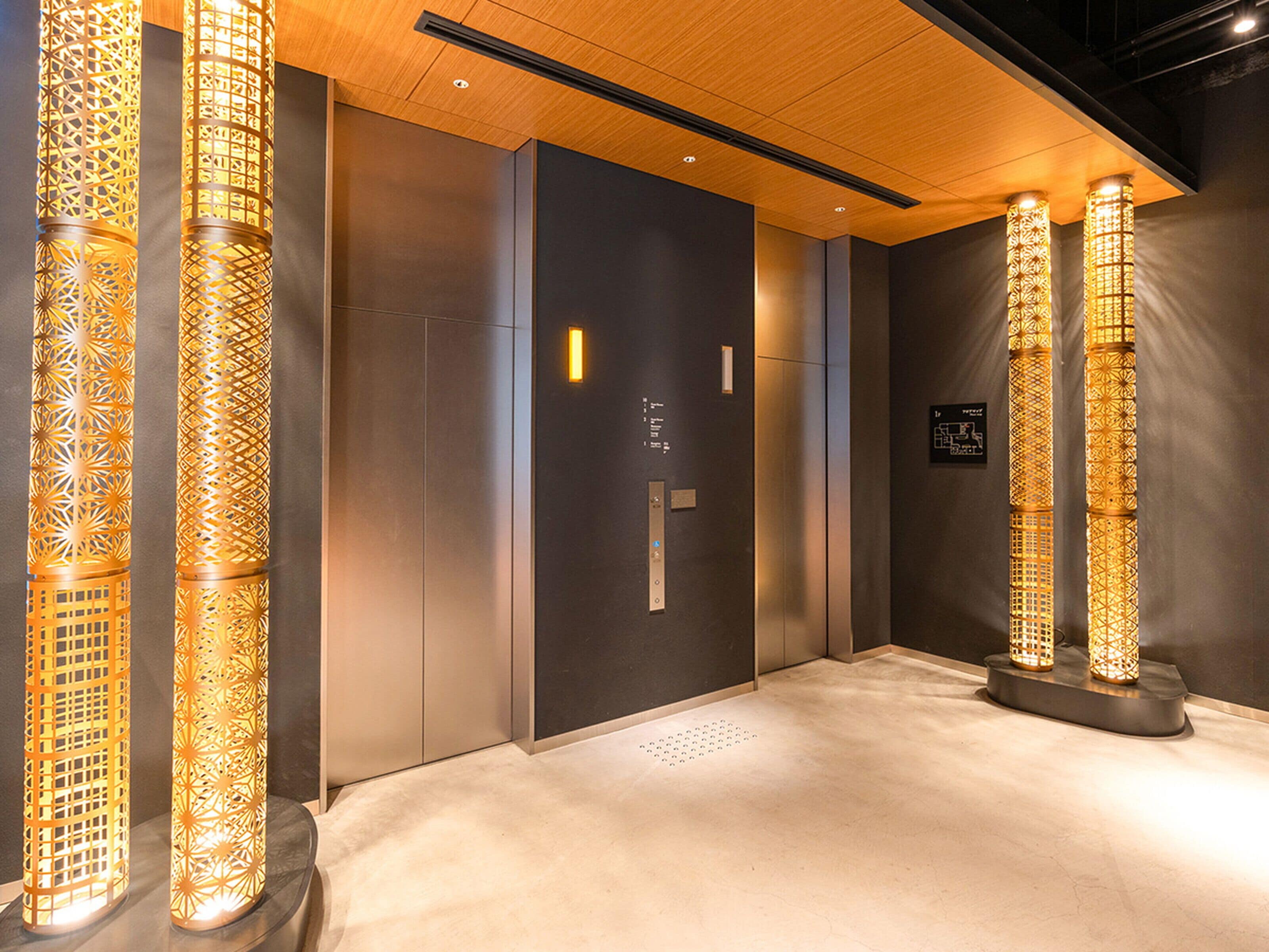 Interior de ascensor con diseño moderno, paredes metálicas y luminarias decorativas.