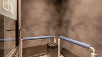 A modern elevator with a metallic finish, glass doors, and a control panel.