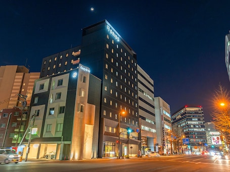 A multi-story hotel with illuminated signage, including "GRIDS" and "CHO GIN" on the facade.