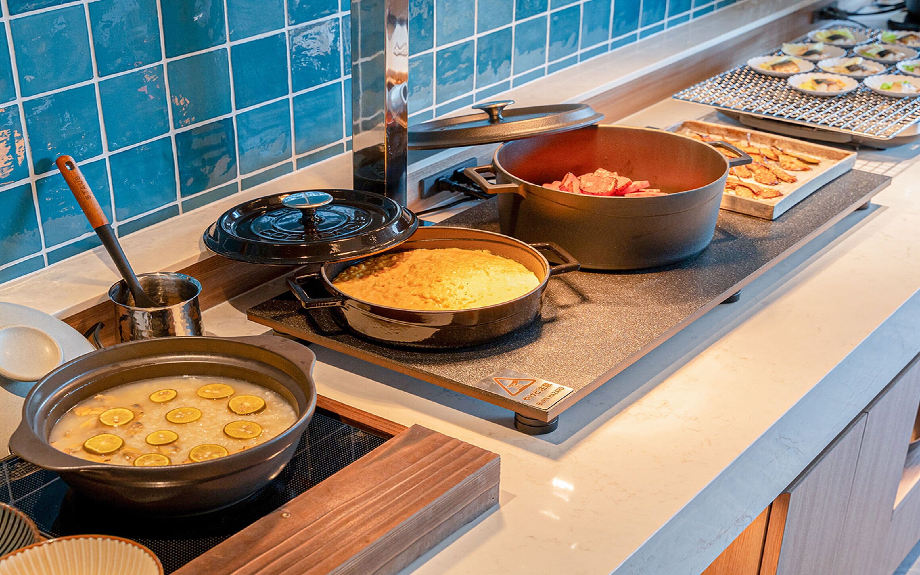 Montaje de bufé con varios platos, entre ellos una olla de sopa, una fuente de comida horneada y una bandeja de aperitivos.