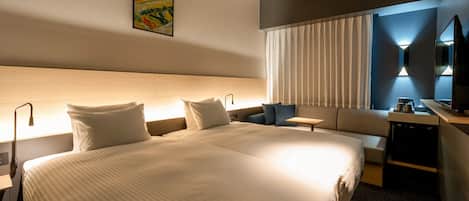 Una habitación de hotel con una cama grande, un sofá, un escritorio con televisor y un cuadro en la pared.
