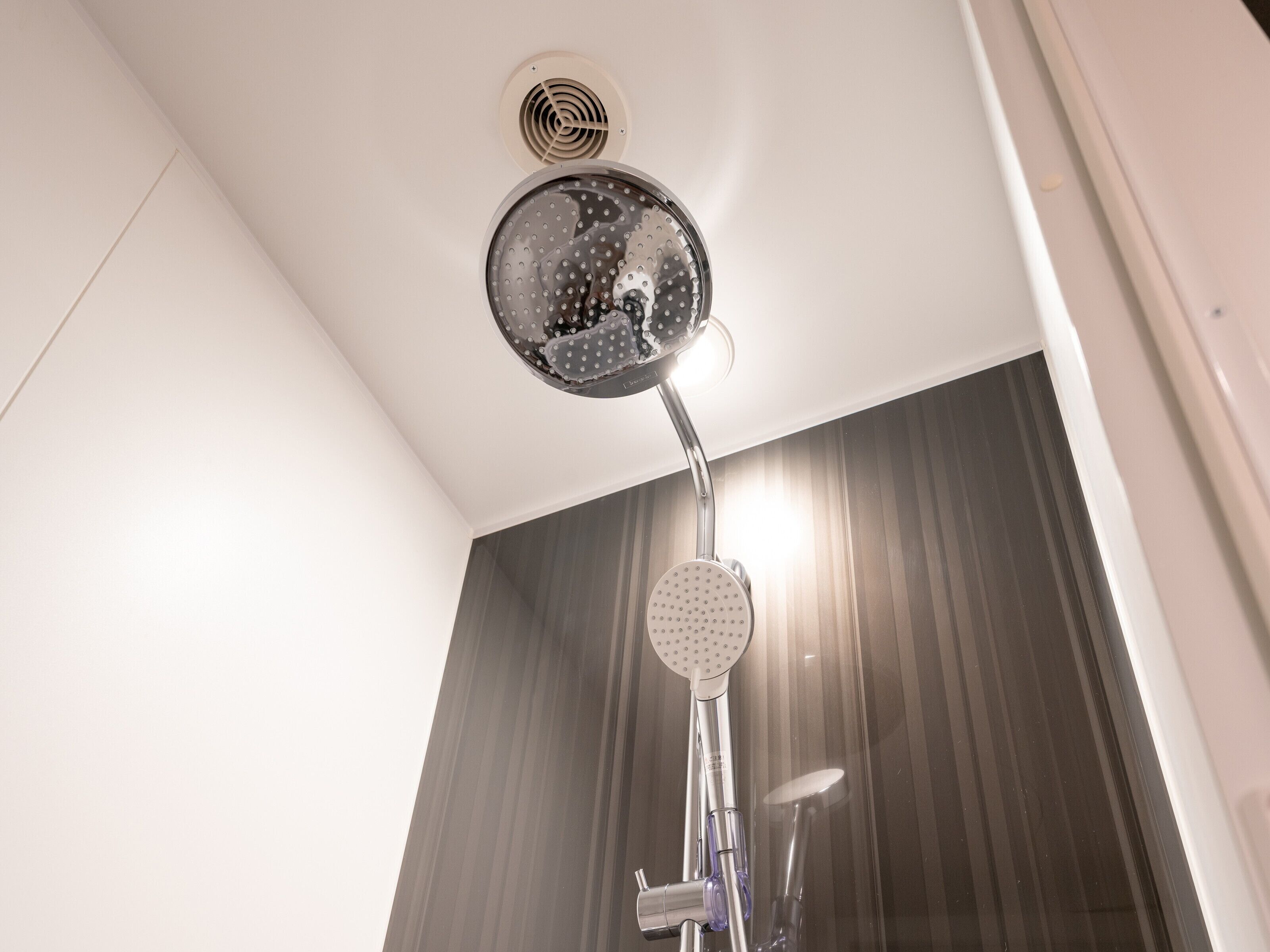 A shower with a circular head and a handheld showerhead.