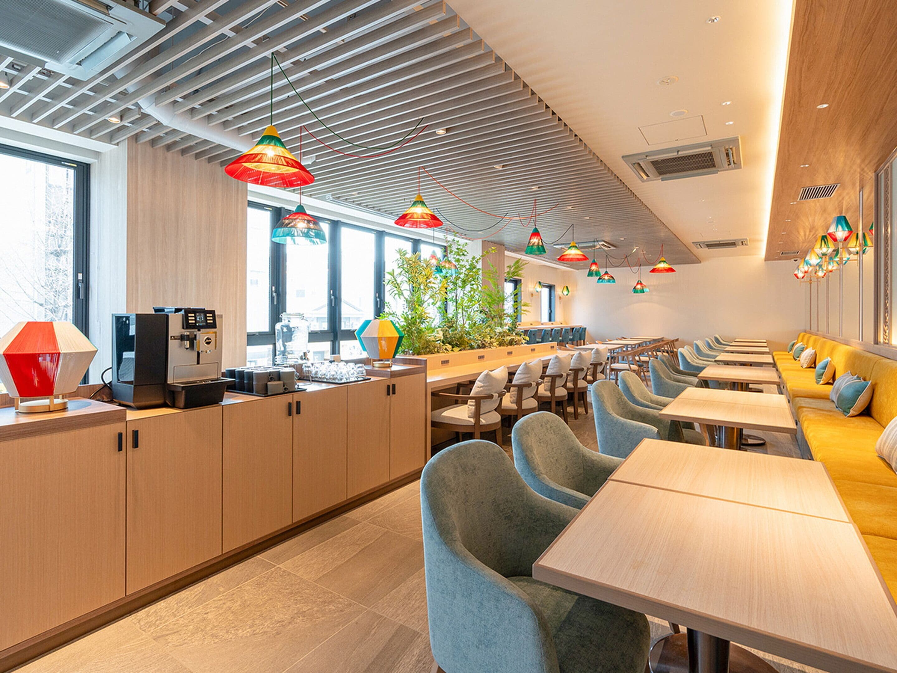 En moderne restaurant med en lang disk, flere siddeområder og farverige hængende lamper.