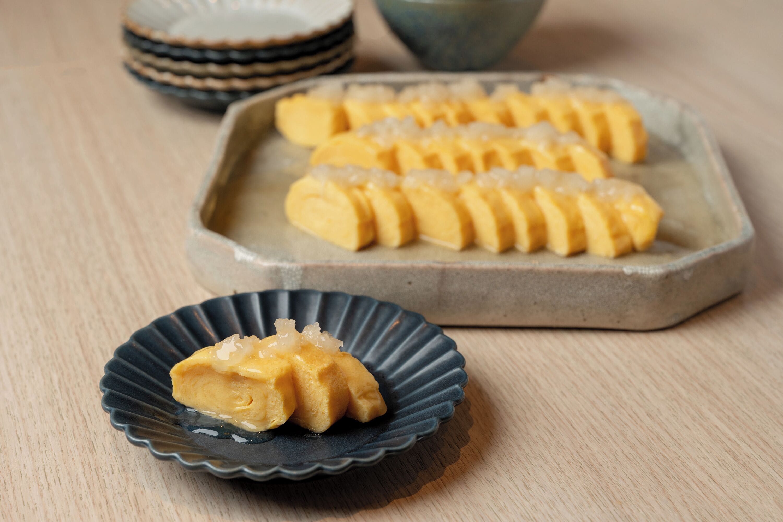A plate of sliced pastries with a small bowl of sauce.