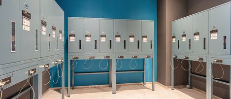 A row of lockers with a blue wall and a grey floor.