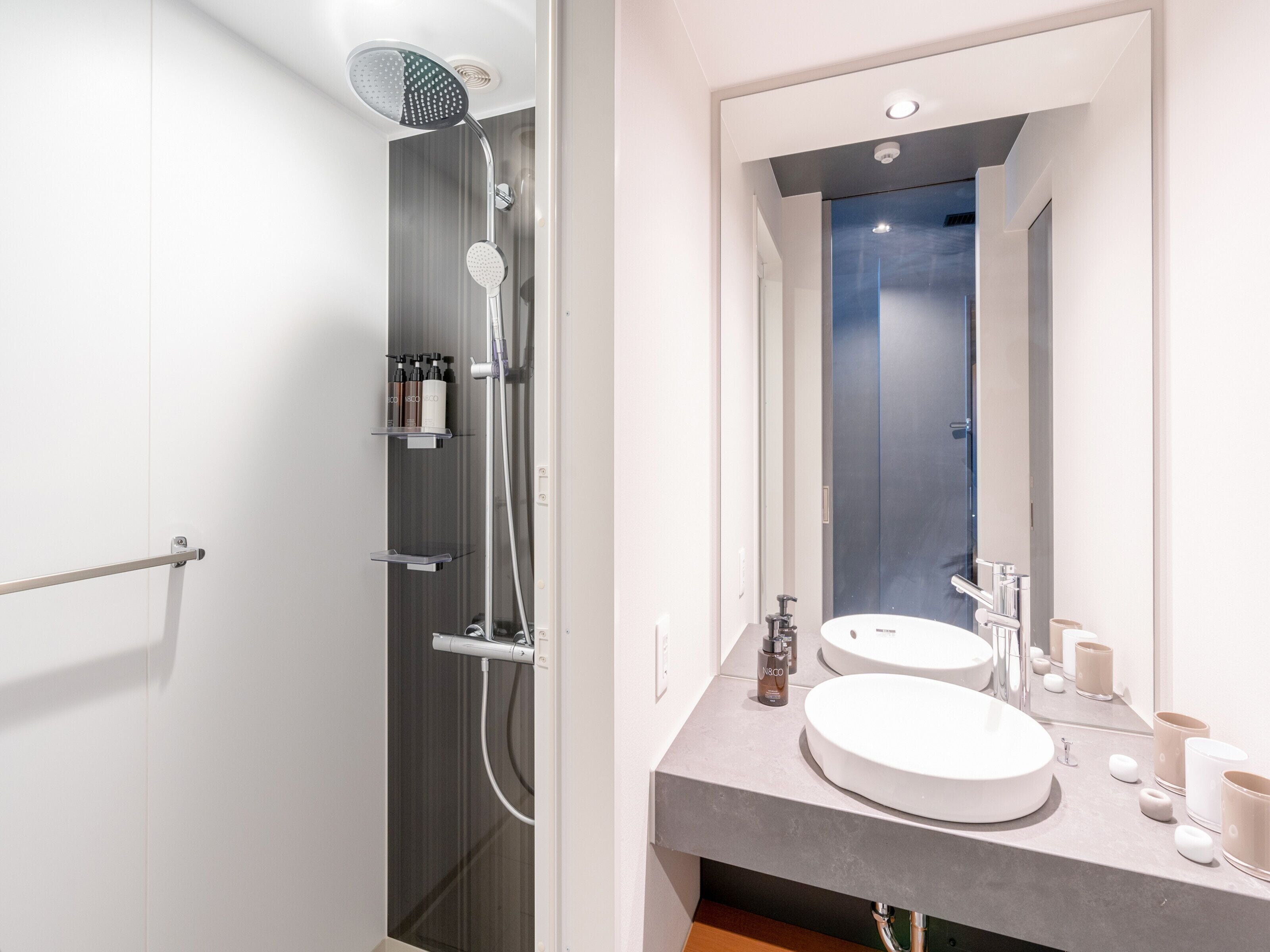 A modern bathroom with a shower, two sinks, and a large mirror.
