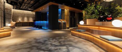 A modern interior with a reception desk, seating areas, and a decorative wall with plants and an umbrella.