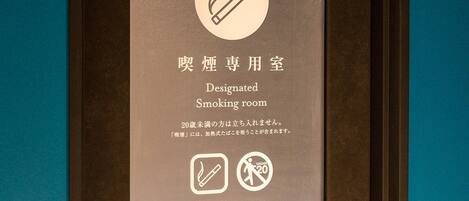 Señal que indica una sala de fumadores designada, con un símbolo de prohibido fumar y advertencia para menores de 20 años.