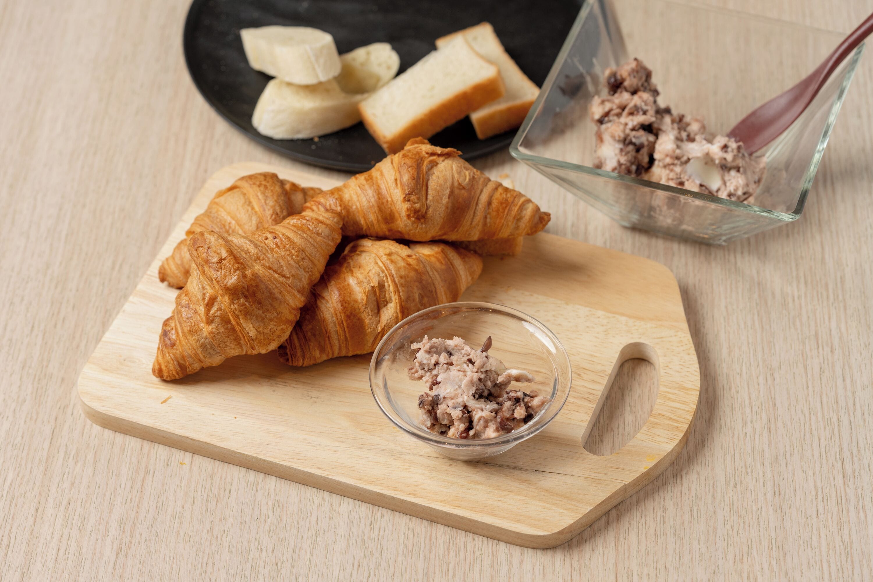 Egy tálca, rajta croissant-okkal és egy kis tálkenyerrel.
