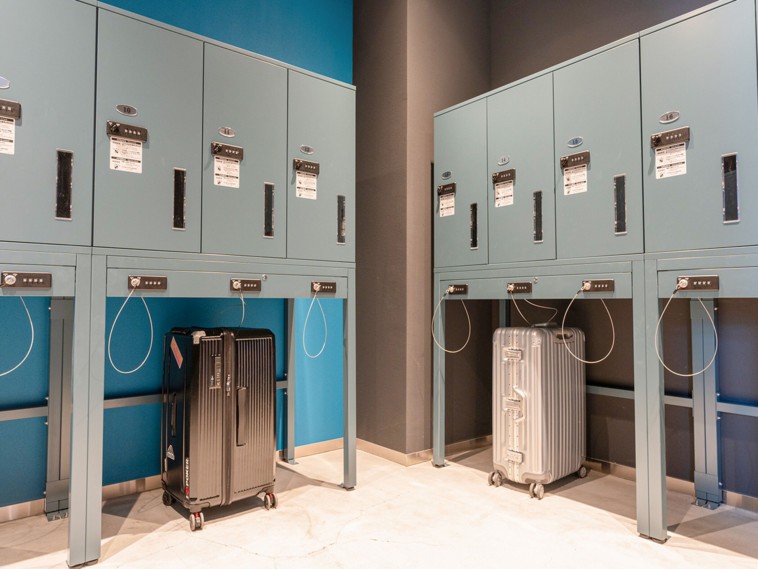 A row of blue lockers with numbered tags, each with a small sign and a cable.
