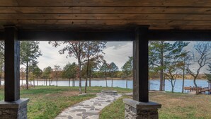A covered outdoor area with a stone pathway leading to a lake. - Gorgeous Mountain Lodge on Privately-Owned Lake - Sleeps 30! (Wilburton)