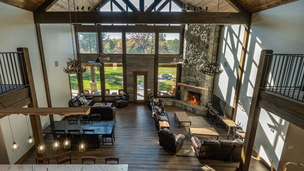 A spacious indoor area with a long dining table, multiple seating arrangements, and a fireplace. - Gorgeous Mountain Lodge on Privately-Owned Lake - Sleeps 30! (Wilburton)