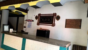Un mostrador de recepción con encimera de azulejos, un letrero de recepción y un panel decorativo en la pared.