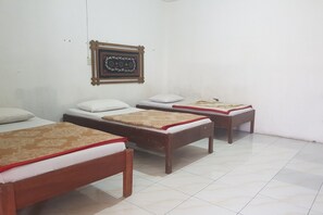 A room with three wooden beds, each with a red and beige bedspread, and a framed picture on the wall. - Hotel O Triarga (Takengon)