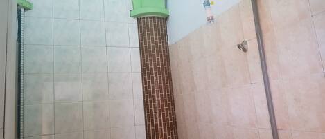 A bathroom with tiled walls, a shower area, and a visible water pipe.