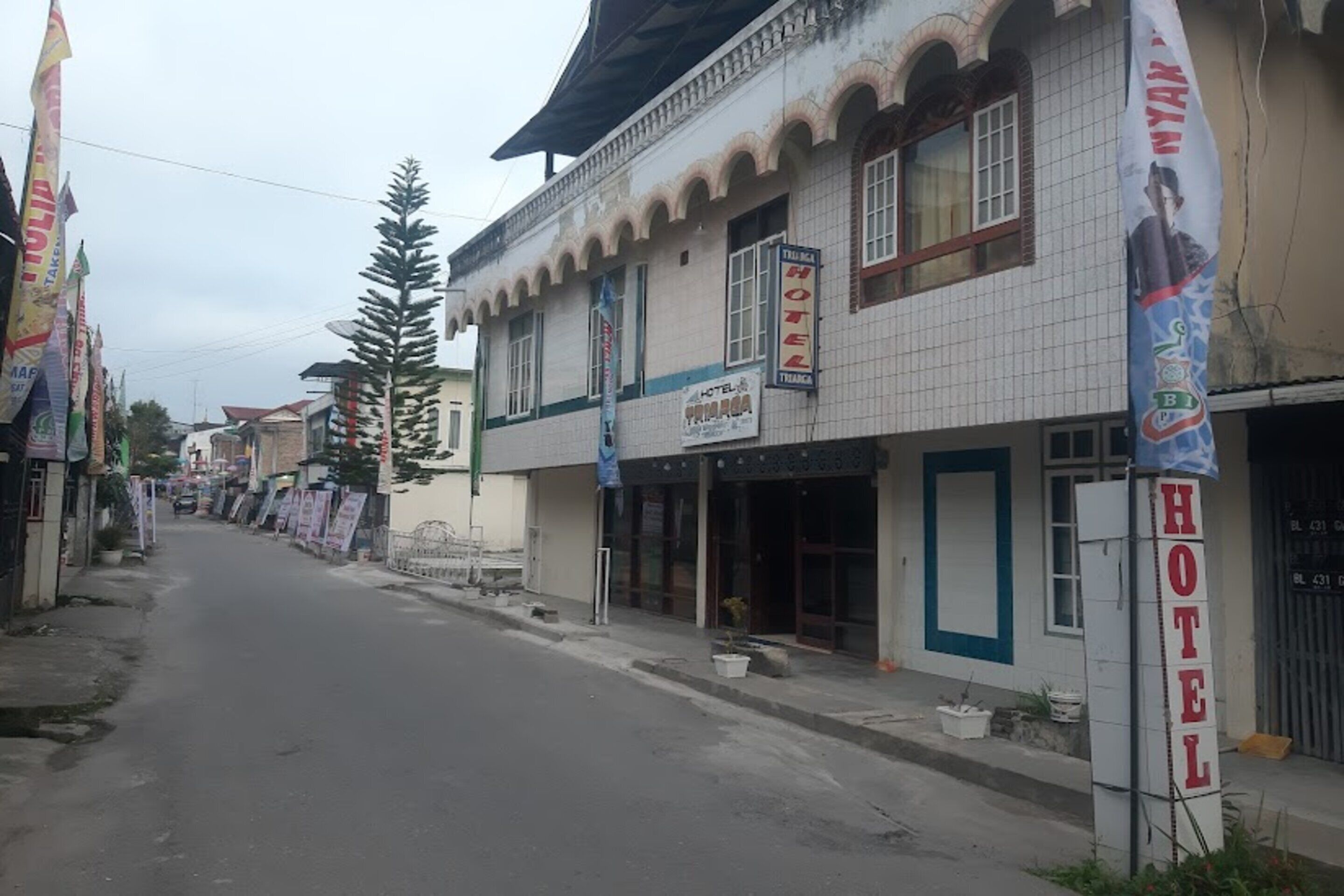 A hotel with a tiled facade, a visible entrance, and a signboard advertising the hotel.