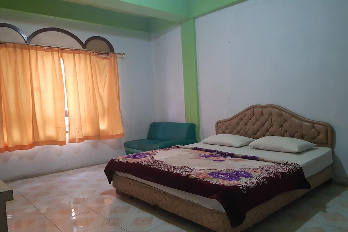 Une chambre à coucher avec un lit, une chaise et une fenêtre avec des rideaux.