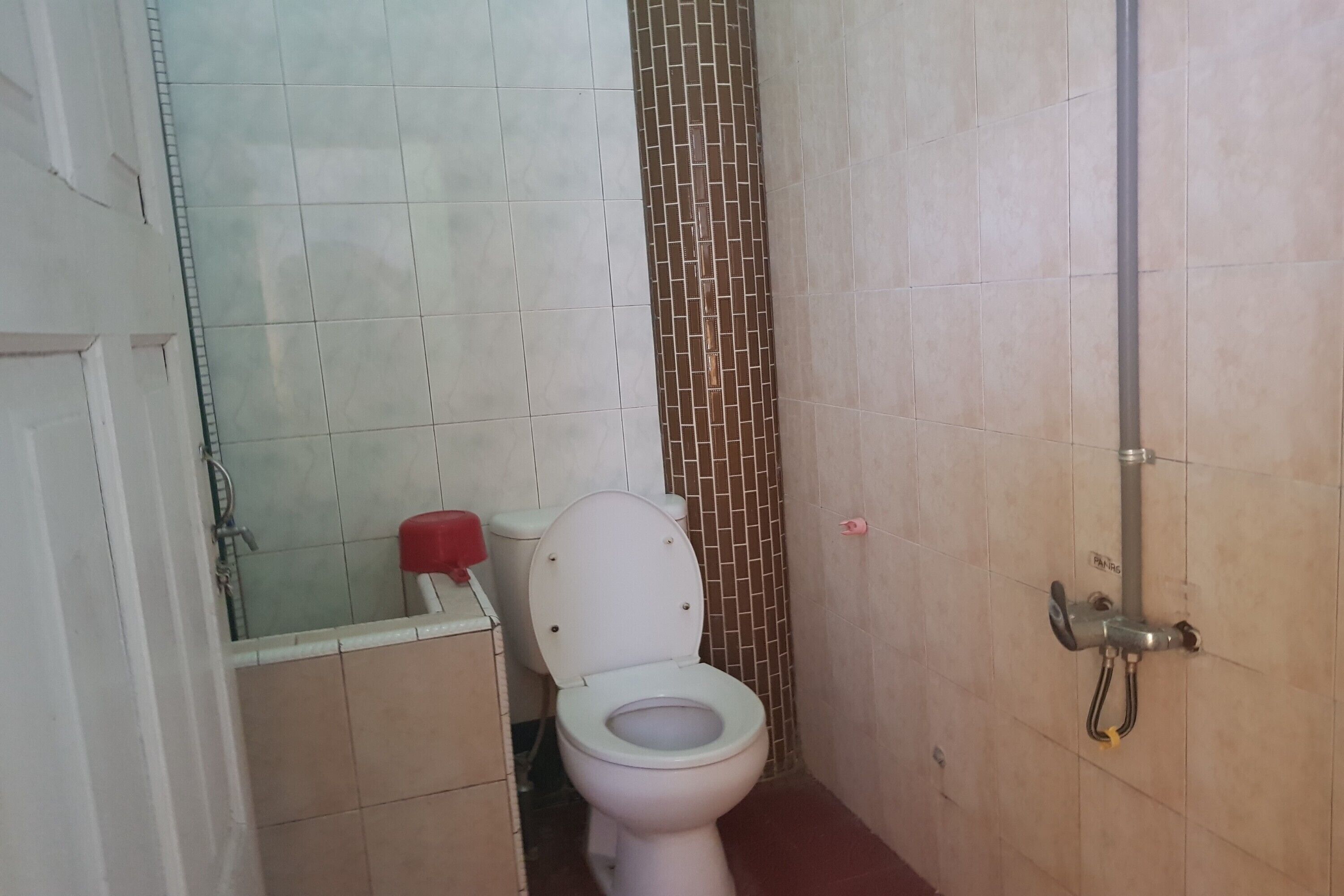 Ein kleines Badezimmer mit Toilette, Dusche und Fliesen.