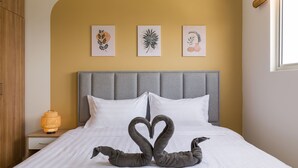 A neatly made bed with two swan-shaped pillows, a bedside lamp, and three framed botanical prints on the wall. - Alanis Sepang at Klia-Klia2 (Sepang)