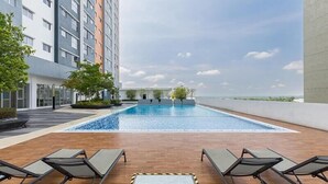 A rooftop swimming pool with lounge chairs, surrounded by a modern building with multiple floors and a clear sky. - Alanis Sepang at Klia-Klia2 (Sepang)
